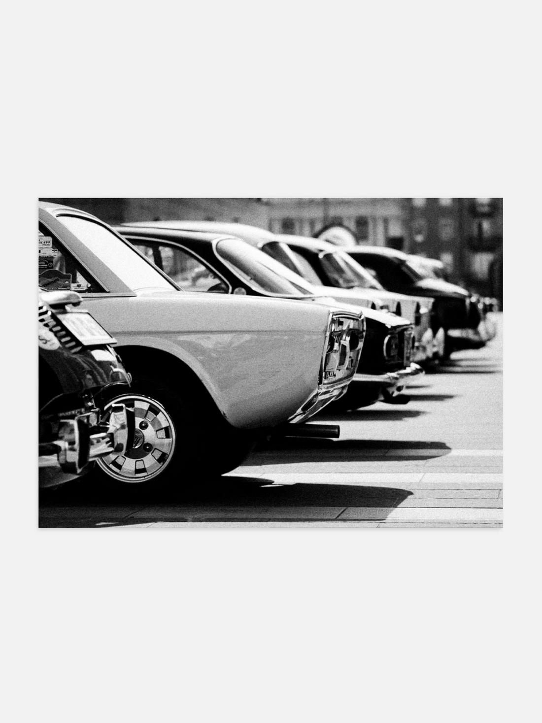 Row of vintage cars parked on a street, black and white photo