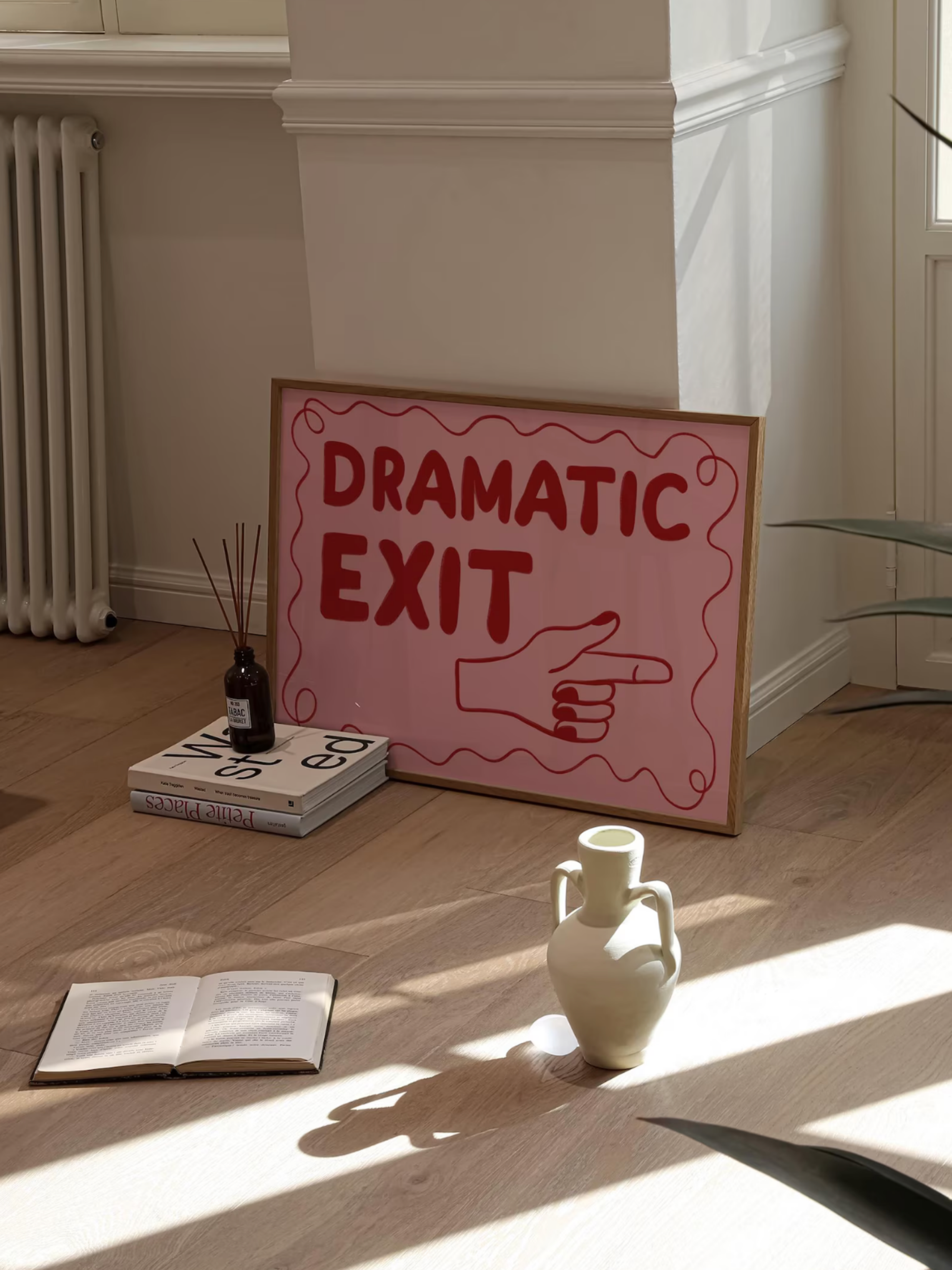 Room interior with a 'Dramatic Exit' sign on the wall, books, and a vase.