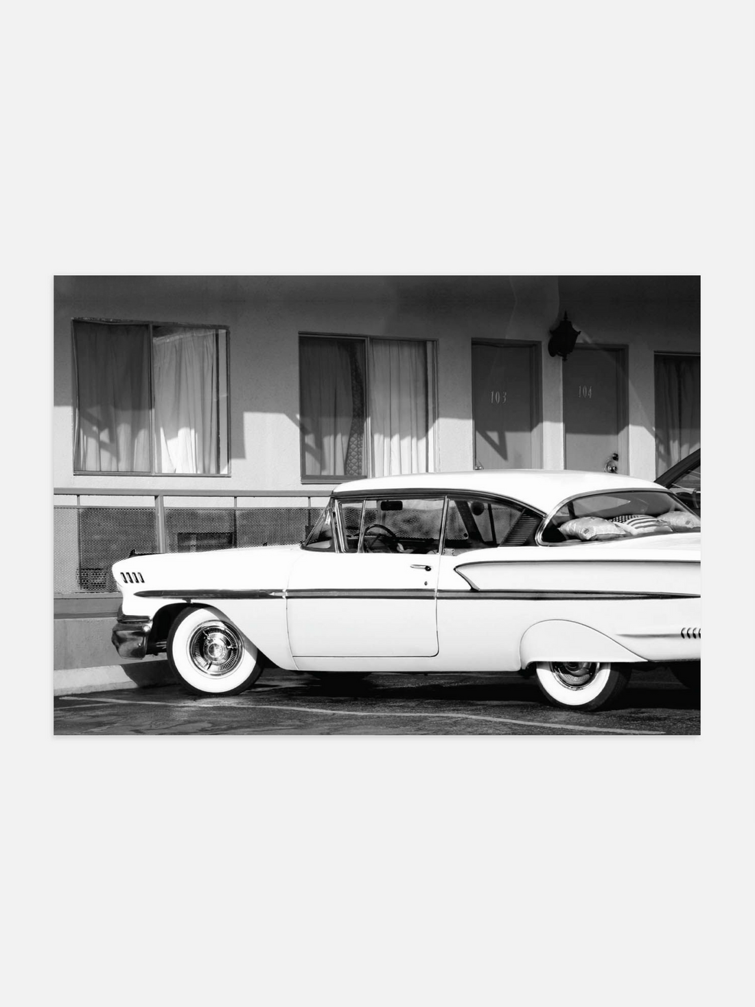 Black and white photo of a vintage car in front of a motel