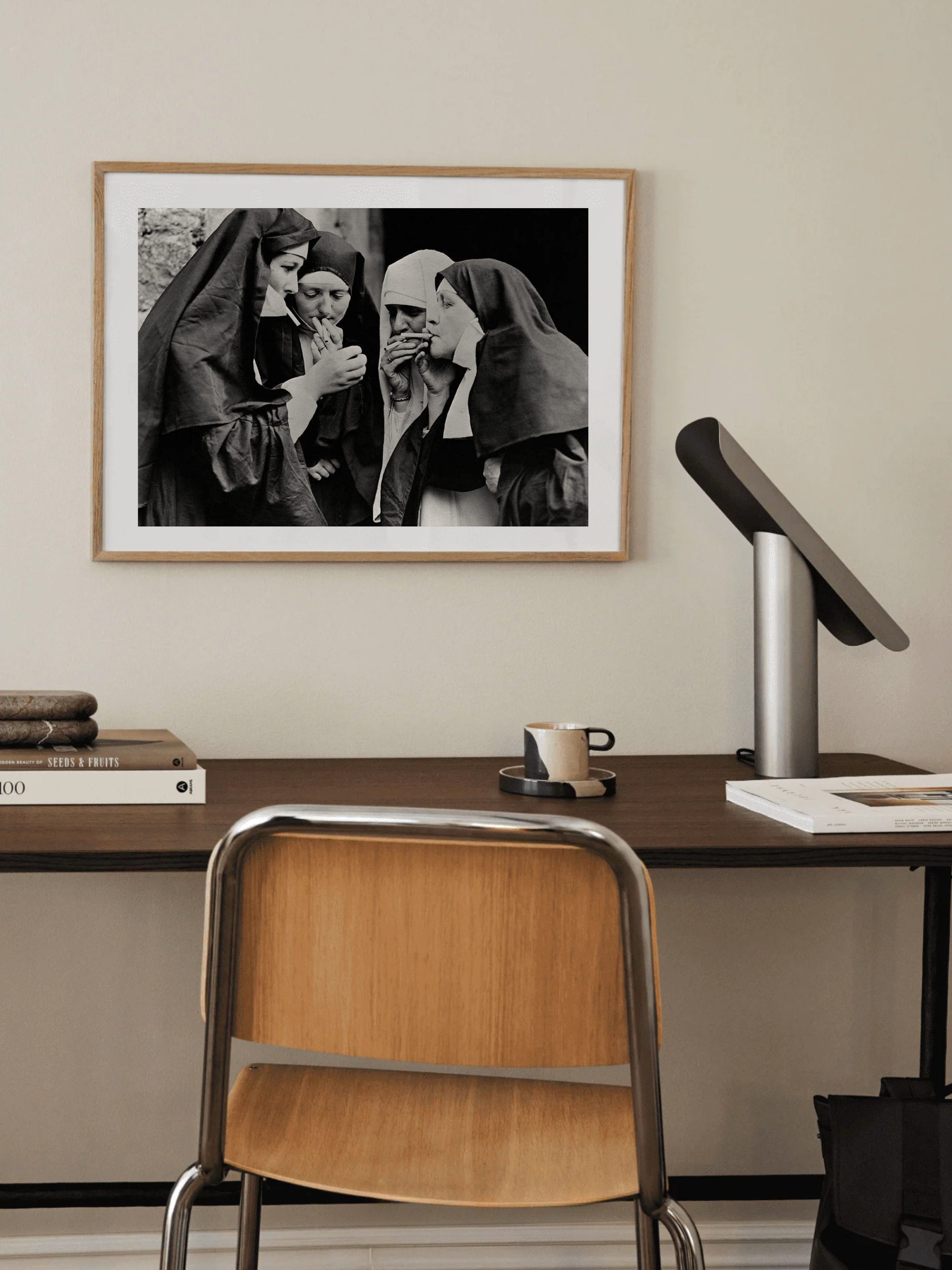 Framed black and white photograph of nuns on a wall above a desk with a chair.