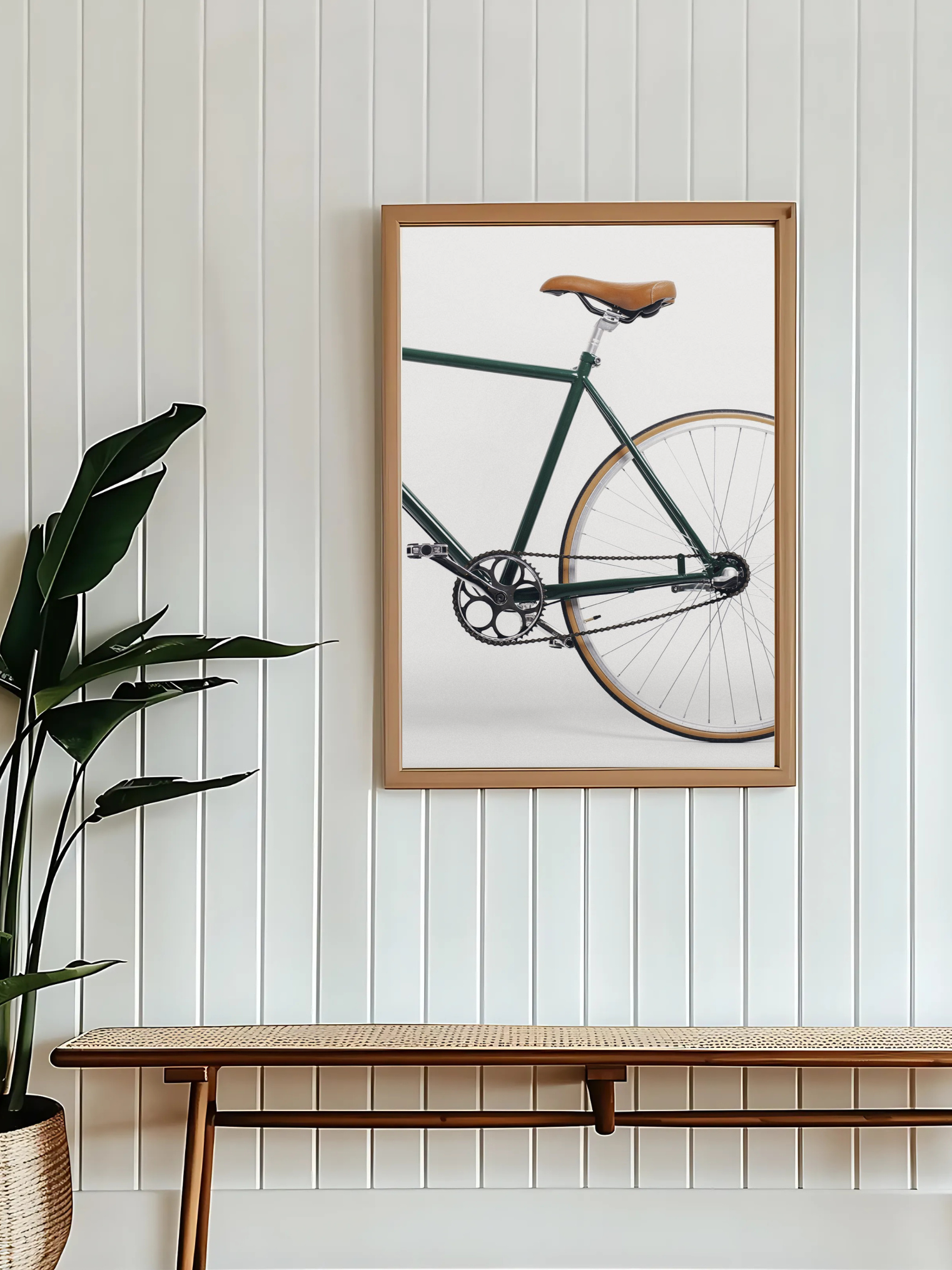 Framed picture of a Green bike print on minimalist beige wall with a plant and wooden bench below.