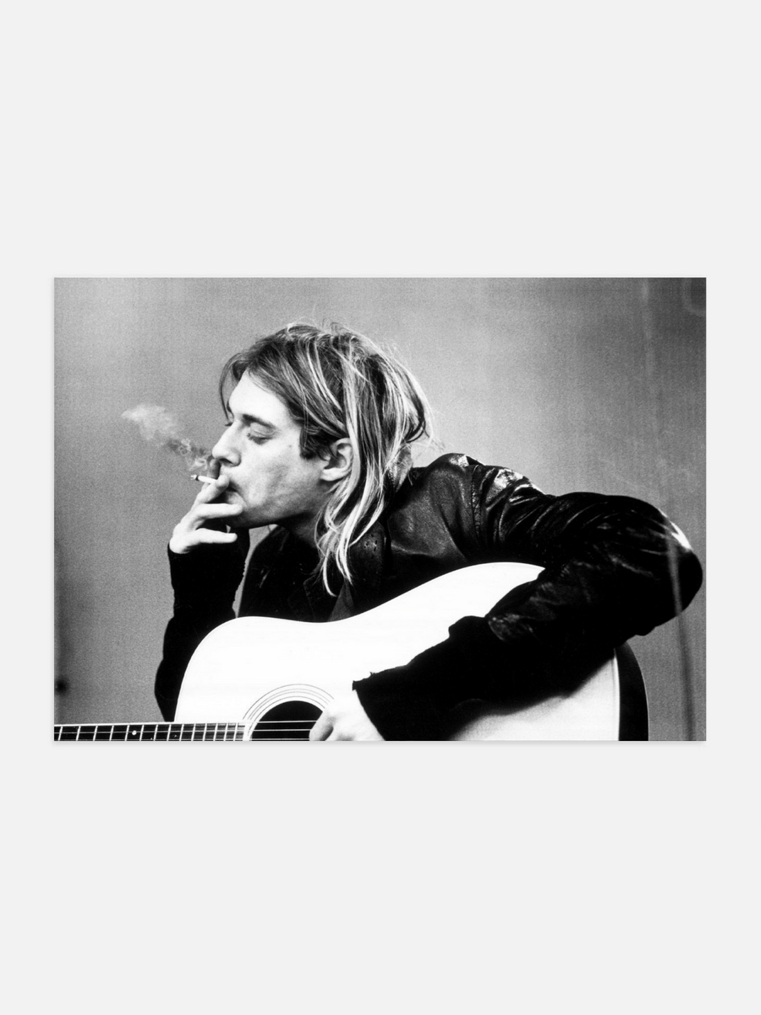 Black and white photo of Kurt Cobain portrait in shadowy monochrome playing guitar and smoking a cigarette.