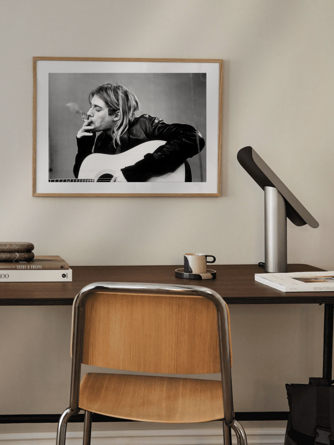 Black and white photo of Kurt Cobain portrait in shadowy monochrome playing guitar and smoking a cigarette.