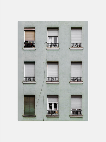 Light green building facade with symmetrically arranged windows featuring various window coverings.