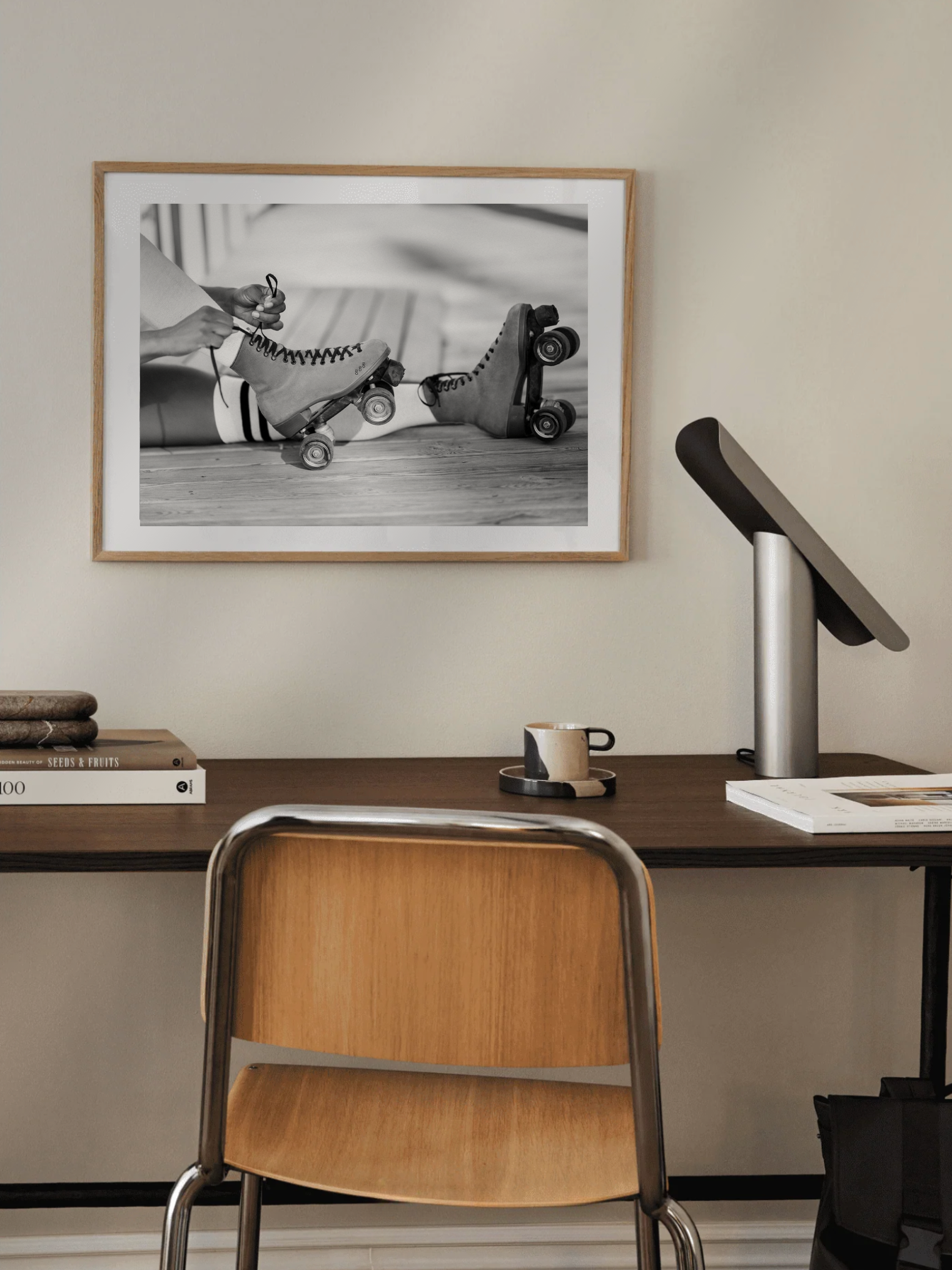 Modern office setup with a framed black and white photo vintage roller disco photograph, desk, chair, and lamp.