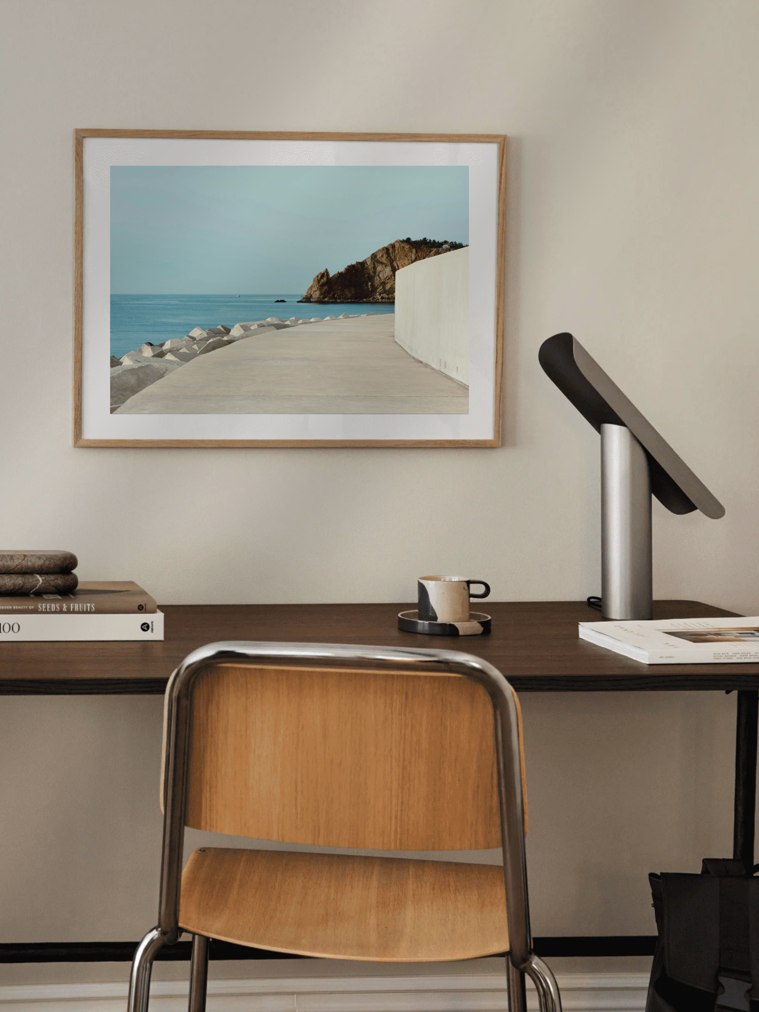 Home office with a desk, chair, and framed of Coastal walkway artwork on the wall.